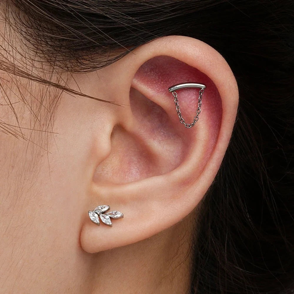 Ear styling photograph with marquise CZ leaf jewelry and other silver-tone pieces.