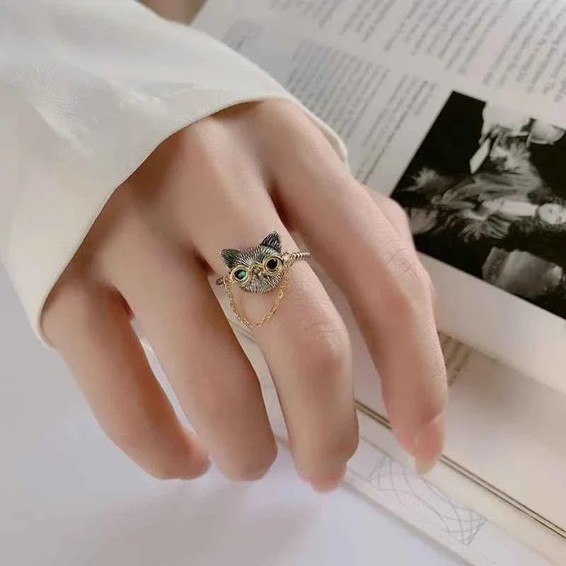Hand wearing a cat eyeglasses ring; a styling photograph rather than a ring-sizing measurement.