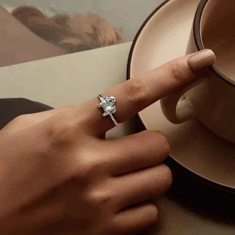 Hand wearing a silver Shih Tzu ring beside a small mirror.