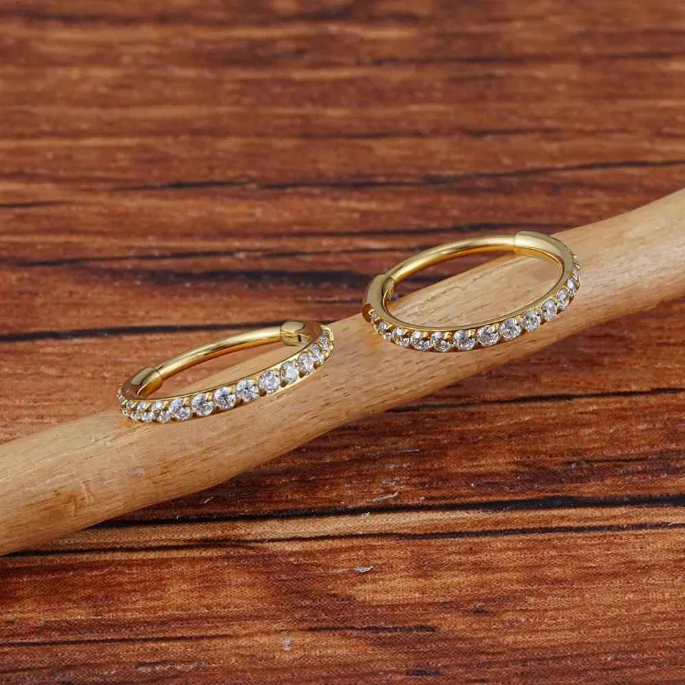Gold-tone and silver-tone CZ hoops photographed together on a wooden branch.