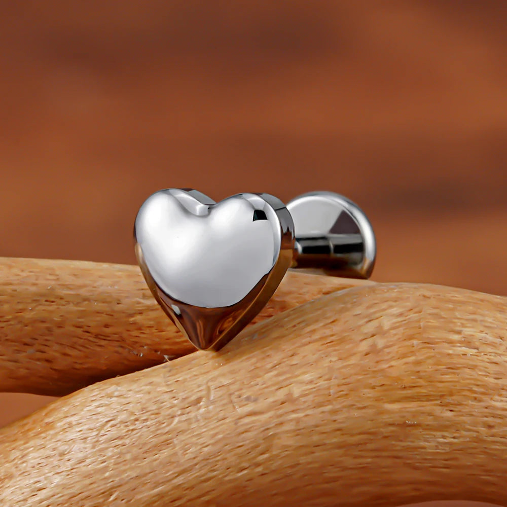 Close-up of polished silver heart flat back labret on a wooden branch