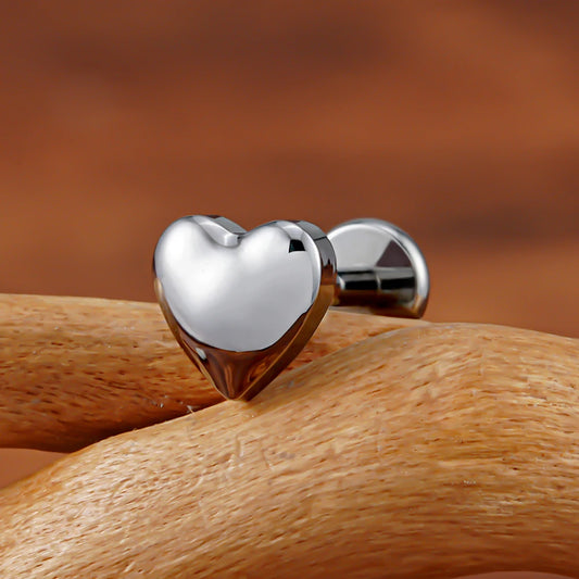 Close-up of polished silver heart flat back labret on a wooden branch