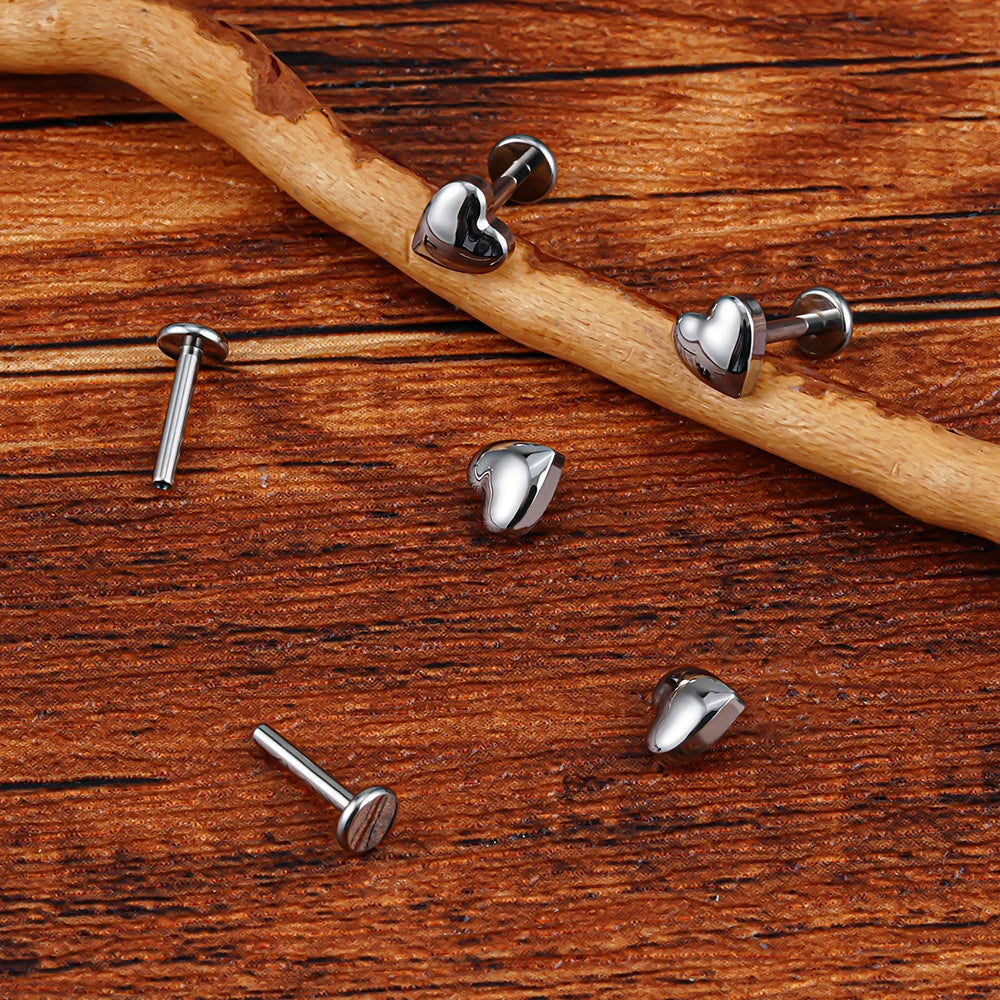 Silver heart labret tops and flat back posts shown separately on wood